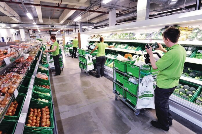 Waitrose staff using handheld technology while managing supermarket stock